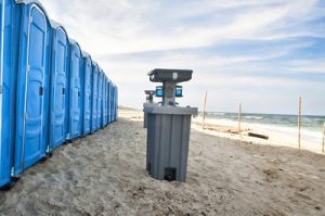 porta potties on a beach with a hand washing station